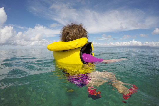 Little child floating with a life jacket alone in the ocean