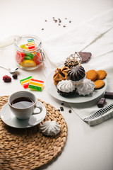 Cup of tea, cookies, a jar of jujube, and sweets on white