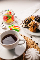 Cup of tea, cookies, a jar of jujube, and sweets on white