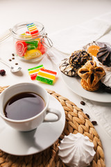 Cup of tea, cookies, a jar of jujube, and sweets on white