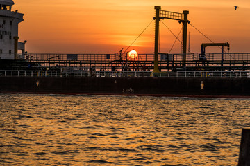 Wooden pier or jetty remains on blue lake sunset and sky reflection water, Thailand.