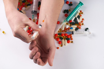 Male hands with medical syringe with drug and different colored medicine and types of pills . Doing inject in vein. On white background.