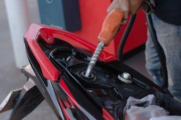 hand fuel nozzle in pouring to motorcycle at gas station
