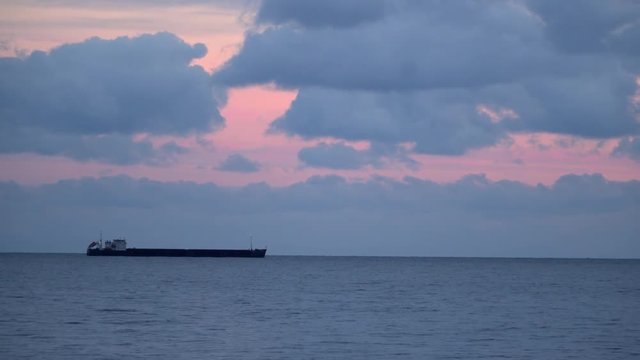 Cargo ship on the horizon. Evening sky with clouds.