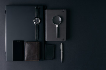 Top view of gentleman set. Magnifying glass, mobile phone, notebook, pen, watch, purse on dark background. Copy space
