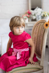 Little girl sitting on a chair, looking to the side