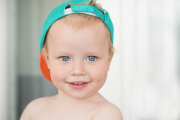 Portrait. Little boy smiling. Green cap, blue eyes
