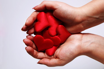 Girl holding a plush red hearts on a white background.