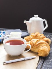 French croissant, glasses, tea and notebook. Workplace concept