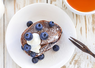Hot tea and buckwheat chocolate pancakes with blueberries
