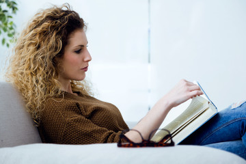 Beautiful young woman reading a book at home.