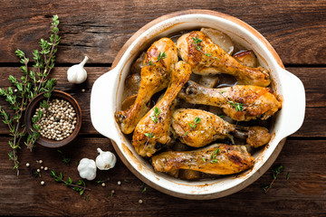 Roasted chicken legs on rustic wooden background, top view