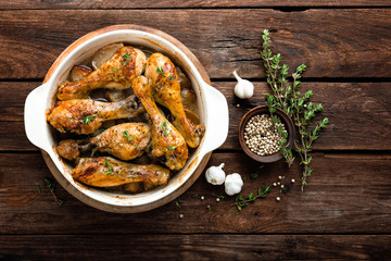 Roasted chicken legs on rustic wooden background, top view