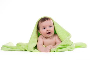 Newborn baby lying down and smiling in a green towel.