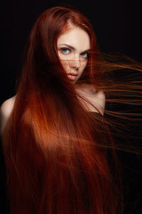 Sexy beautiful redhead girl with long hair. Perfect woman portrait on black background. Gorgeous hair and deep eyes. Natural beauty, clean skin, facial care and hair. Strong and thick hair. Flower