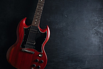 Top view of red electric guitar on dark wooden background - obrazy, fototapety, plakaty