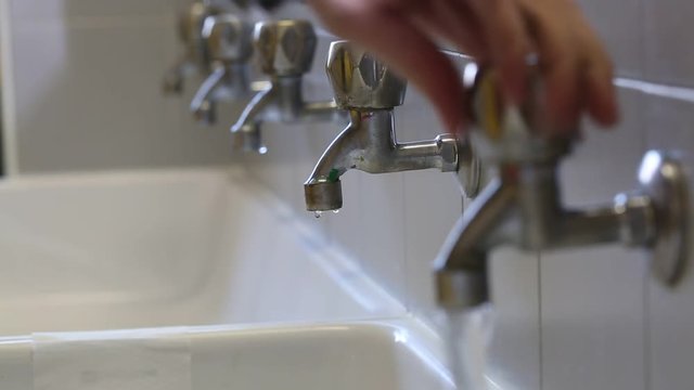 hand closes the water to many taps in the school bathroom to avoid wasting