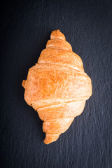 Fresh croissant on a black slate background. Top view