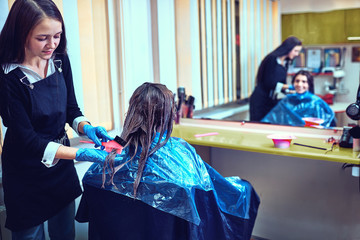 Brunette woman dying her hair at the beauty salon
