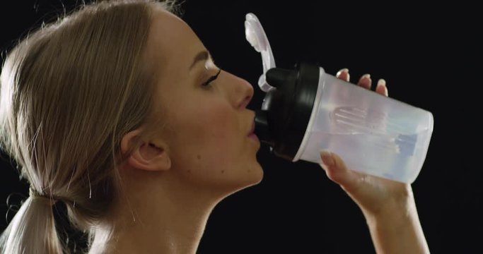 Fit and sporty blonde woman in workout outfit drinking water