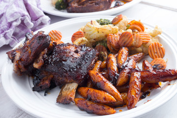 Slow cooked ribs with homemade pasta and grilled vegetables served on a wooden table