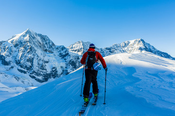 Fototapeta na wymiar Mountaineer backcountry ski walking up along a snowy ridge with
