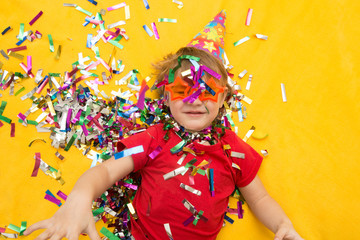 Happy kid celebrating party with blowing confetti top view
