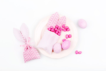 Easter table setting. Painted eggs Bunny treat bag with pink candy. Flat lay, top view