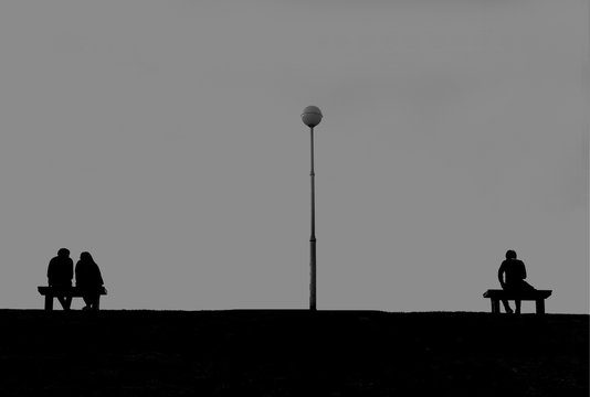 The silhouette of two groups; person sitting alone with grey sky with lonely, sad, alone, person space and couple sitting together with love and happiness concept of various emotions in Valentine day 