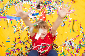 Obraz na płótnie Canvas Happy kid celebrating party with blowing confetti top view