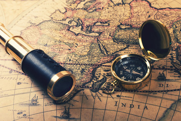 vintage compass and spyglass on old world map