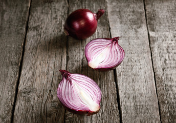 close up of sliced red onion and whole red onion on a wooden tab