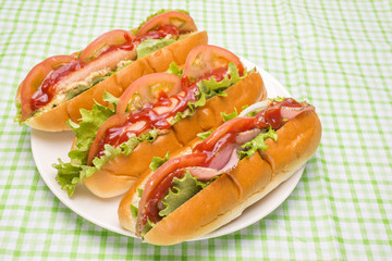 皿の上の3本のホットドッグとパストラミサンド