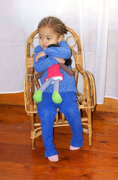 sad child sulking and cuddling her dolly