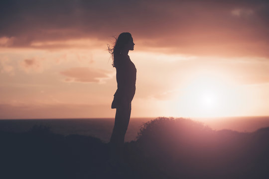 Black silhouette of pretty girl on sea beach at sunset