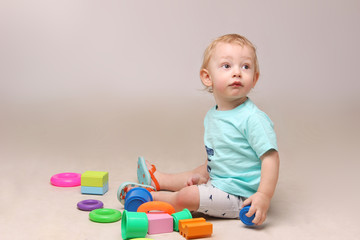 Studio shot of an adorable baby boy sitting on the floor and playing with some toys.