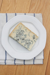 Fetta di gorgonzola su piatto su tavolo di legno