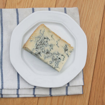 Fetta di gorgonzola su piatto su tavolo di legno