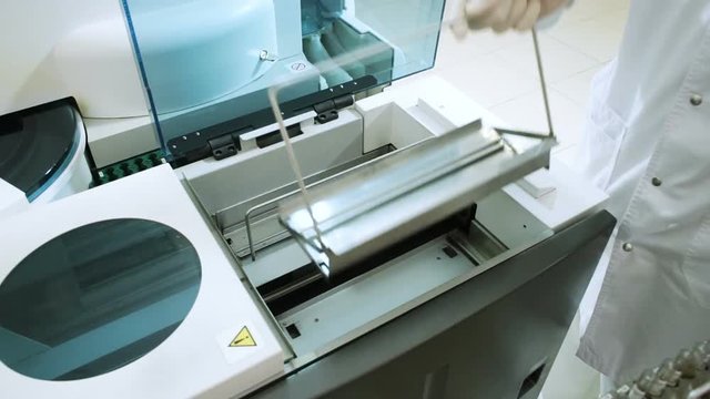 Laboratory analysing of blood. Female laboratory assistant analyzing samples of blood at modern equipment. HD