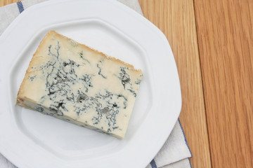 Fetta di gorgonzola su piatto su tavolo di legno