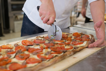 Obraz na płótnie Canvas Pizza maker cutting focaccia romana