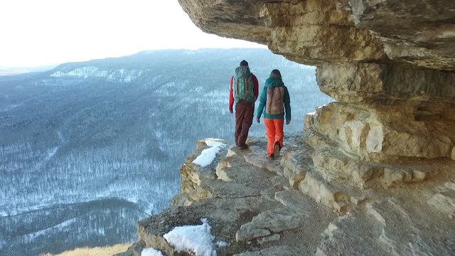 Couple of travelers walking on edge of cliff