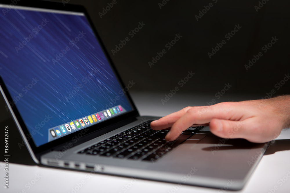 Wall mural hand typing on a keyboard of laptop with operating system screen on background