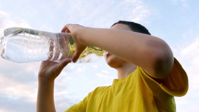 A boy drinking water from a plastic bottle. Slow motion