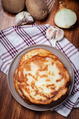 Stack of potato pancakes on a wooden table. In the background po
