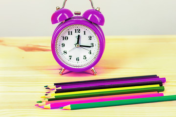 Back to school. colored pencils and an alarm clock,