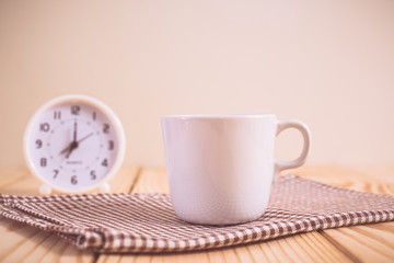 Coffee cup and clock on wood table. vintage color effected