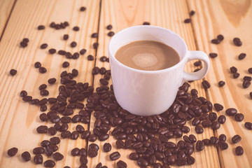 Coffee cup and coffee bean on wood table. vintage color effected