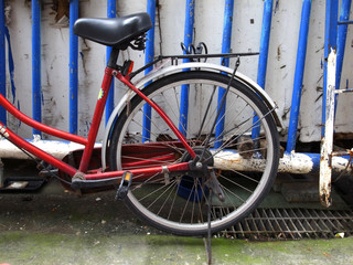 Fototapeta na wymiar Red bicycle parked in front of blue and white railings.