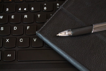 Pen with notebook on keyboard.